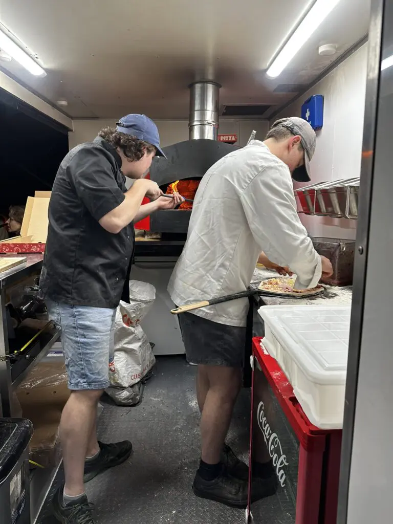 two men in wood-fired pizza trailer
