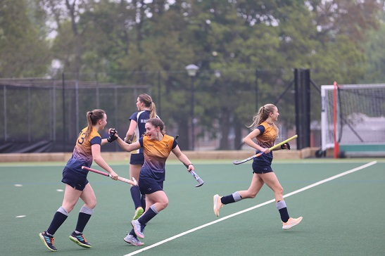 girls celebrating a goal on the hockey astroturf 