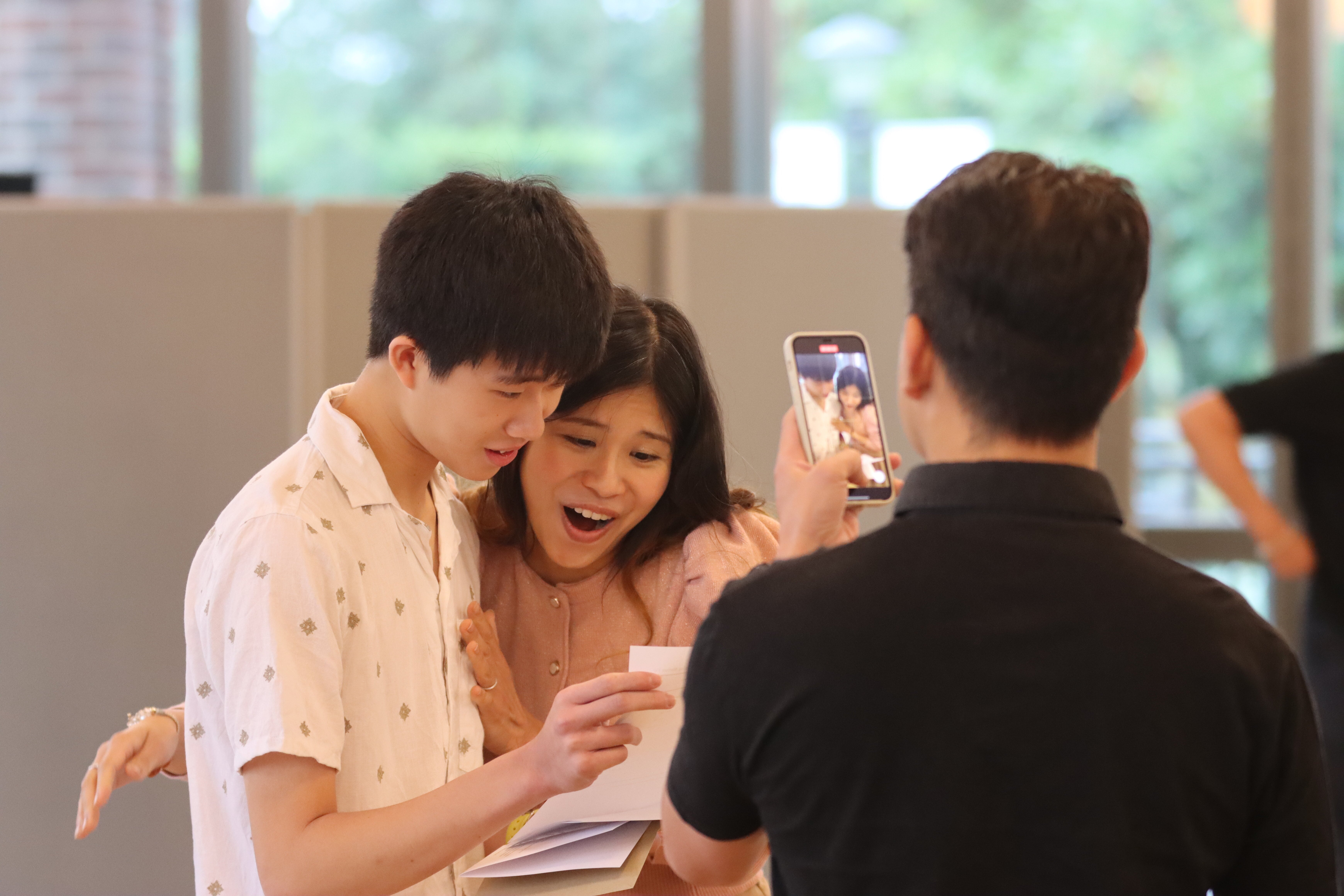 dad taking a video of mother and son opening GSCE results