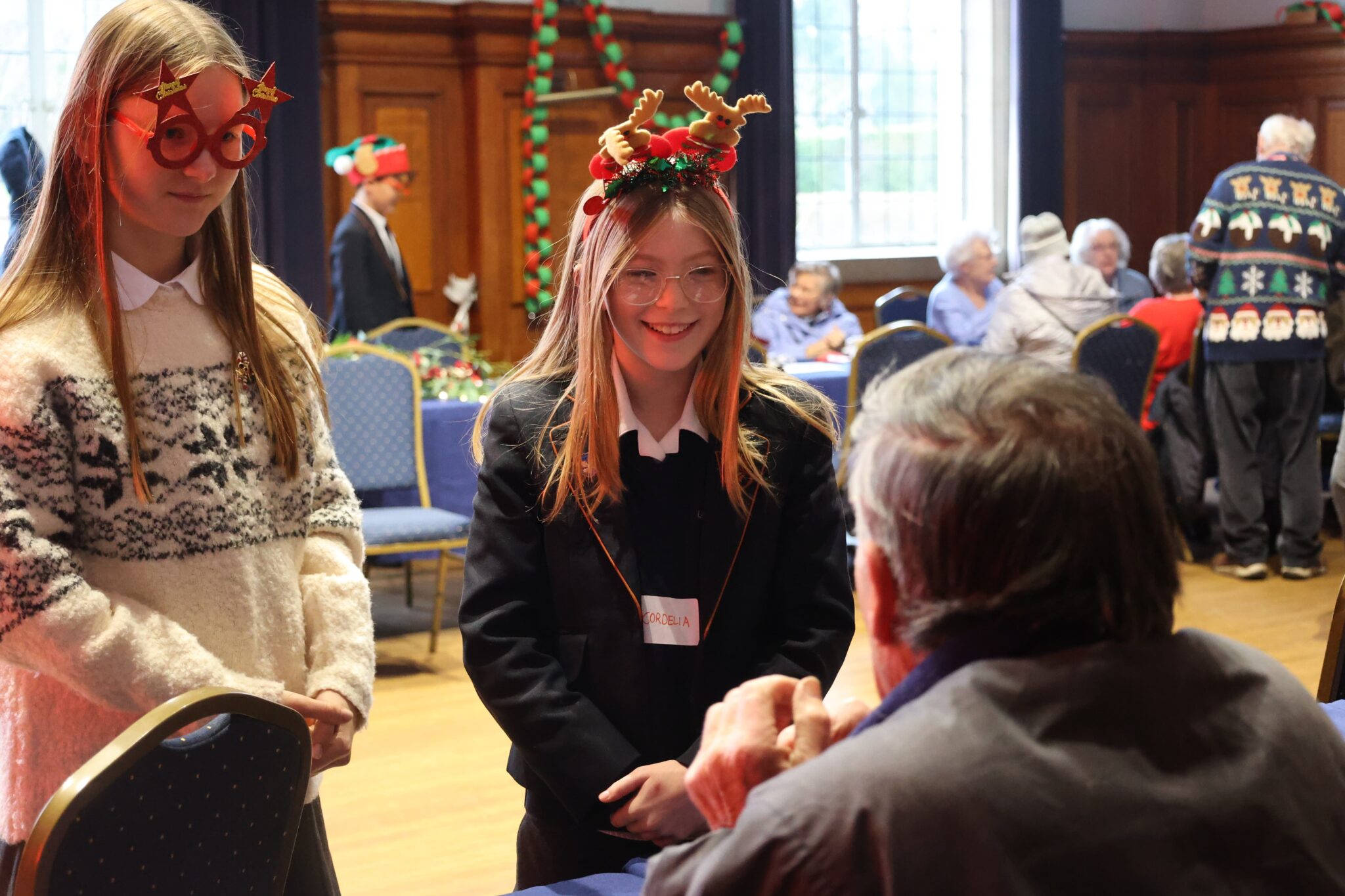 Leighton Park students with Christmas accessories talking to an elderly man