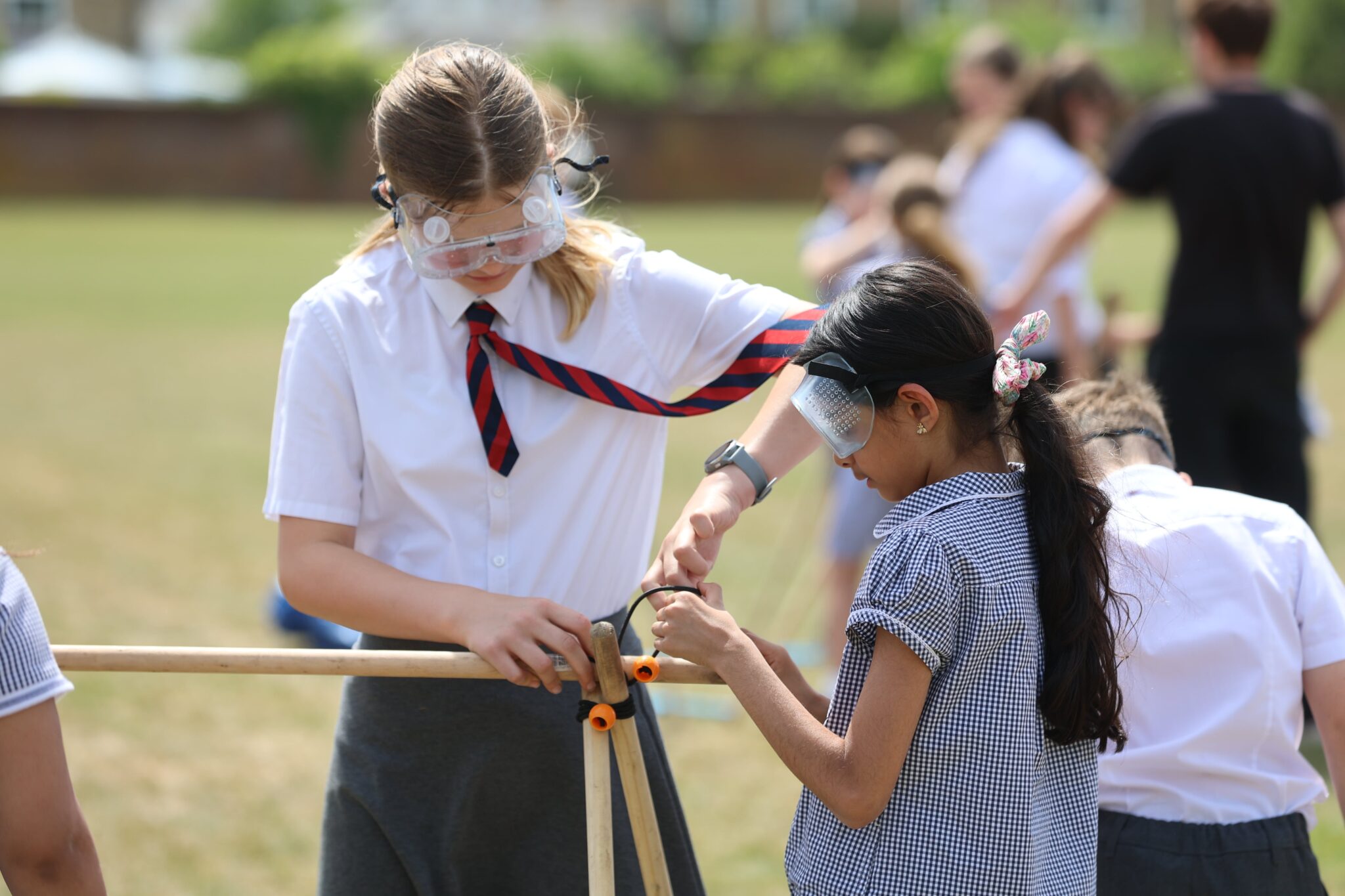 school girls sawing a wooden post